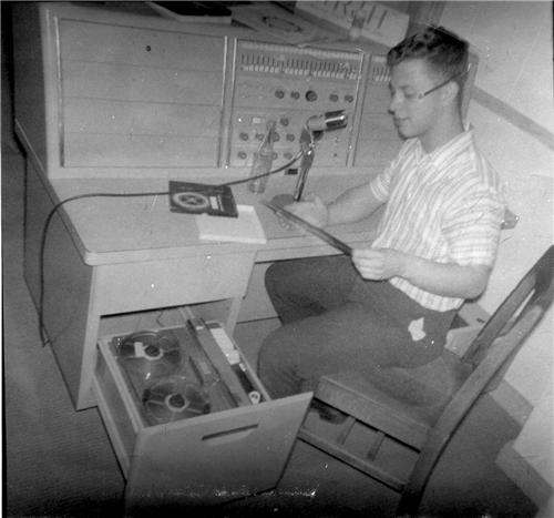 Charles seated at an audio console speaking into a microphone announcing the morning messages at Roosevelt Junior High School in 1963.